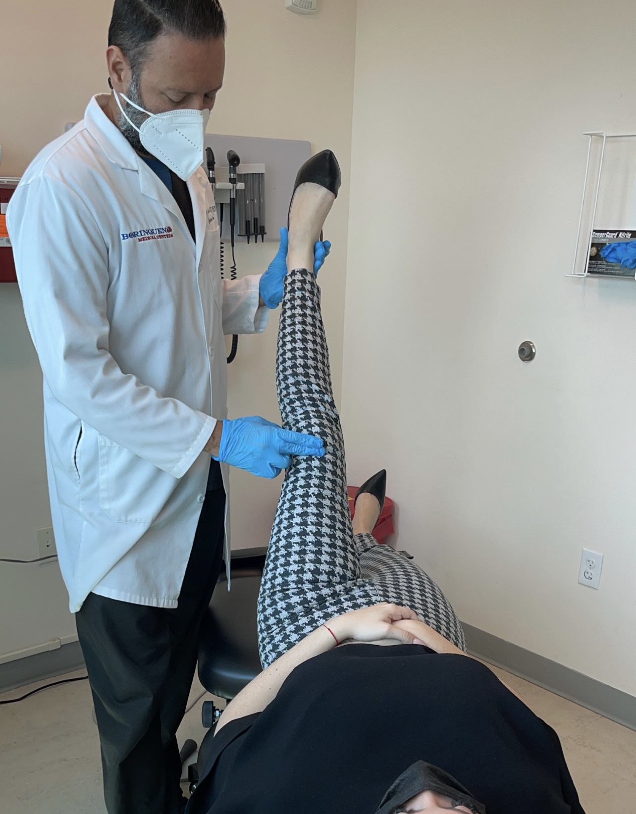 Male chiropractor adjusting the leg of a woman in a medical office.